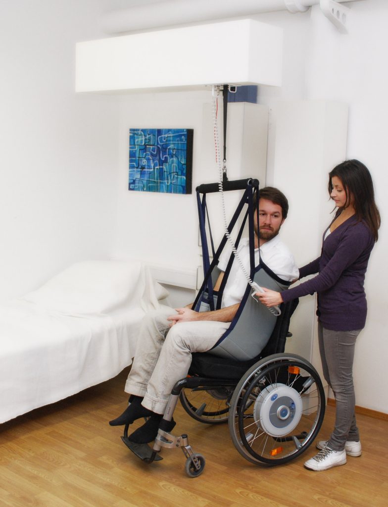 Photo showing a patient being transferred from wheelchair using a patient lift