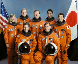 Official portrait includes the seven crewmembers wearing launch and entry suits (LESs). These seven crewmembers are currently in training for the STS-47 Spacelab J (SLJ) mission scheduled for later this year. Pictured are (left to right, front) Mission Specialist (MS) Jerome Apt and Pilot Curtis L. Brown, Jr (both holding launch and entry helmets (LEHs)); and (left to right, rear) MS N. Jan Davis, MS and Payload Commander (PLC) Mark C. Lee, Commander Robert L. Gibson, MS Mae C. Jemison, and Japanese Payload Specialist Mamoru Mohri. Mohri is representing the National Space Development Agency of Japan (NASDA). In the background are the flags of the United States (U.S.) and Japan. Portrait was made by NASA JSC contract photographer Robert G. Markowitz.