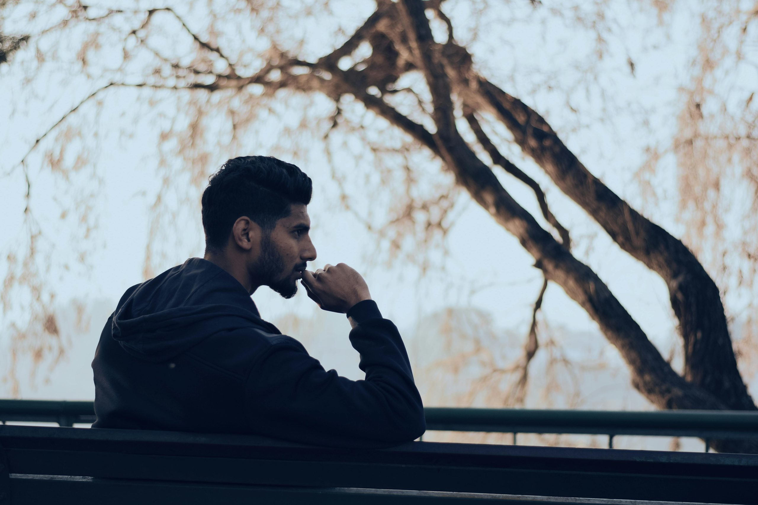 photo of a man sitting on a bench in a park