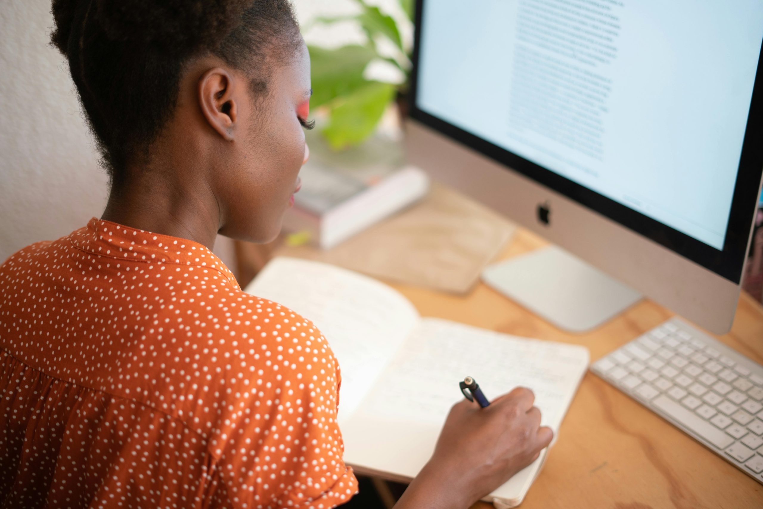 woman writing while working on computer