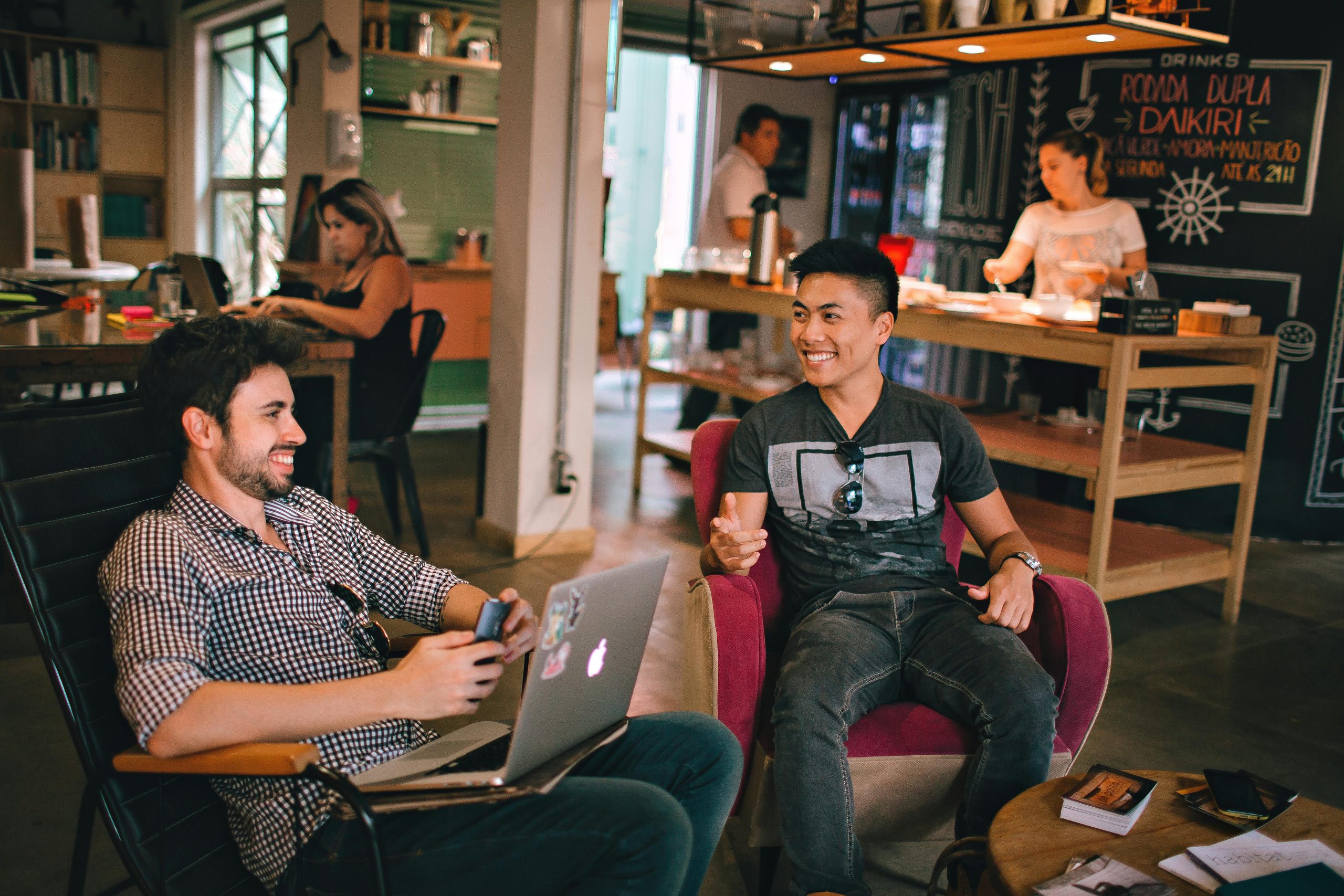 two men speaking together and smiling in a cafe