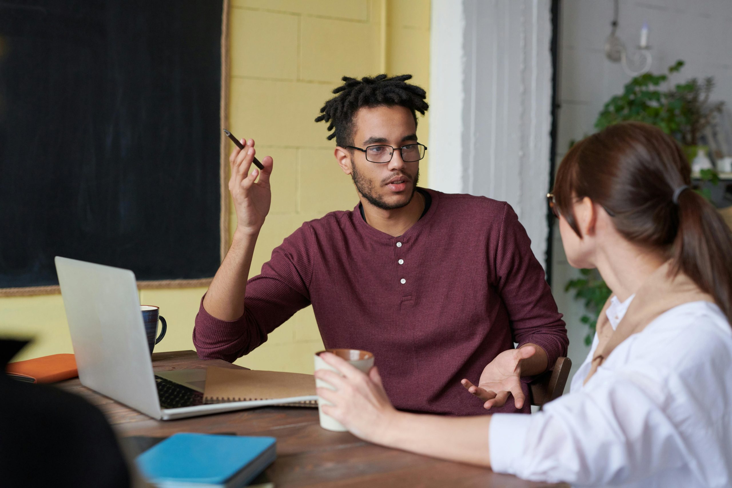 photo of a man and woman discussing something in front of a laptop